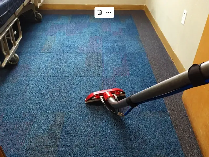 Carpet extraction wand pulling water through blue commercial carpet tile in an office