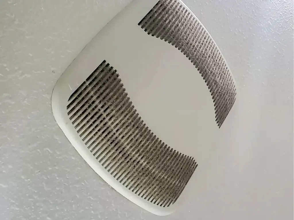 Before: bathroom exhaust fan cover on a textured ceiling