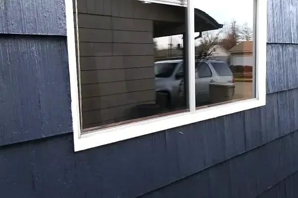 Clean exterior window in dark grey shingle siding